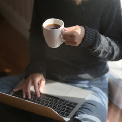 Person sitting with laptop and cup of coffee