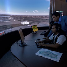 Two people carry out air traffic management simulation exercises at Cranfield University looking at a large digital airport screen