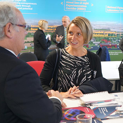Two people stand behind a desk talking. 