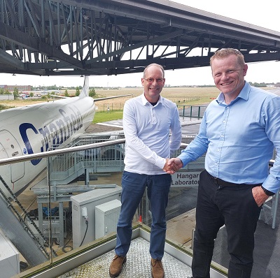 Rick Cudworth and David Denyer shake hands in front of Cranfield's aircraft at the university campus