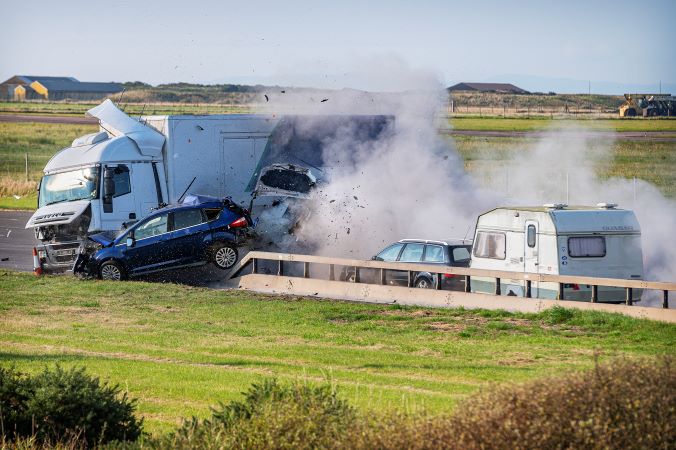 The moment of impact shows a white lorry with a blue vehicle crashing into it. Smoke and debris and other cars