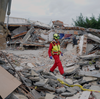 A recovery worker goes through a built up area damaged by an earthquake