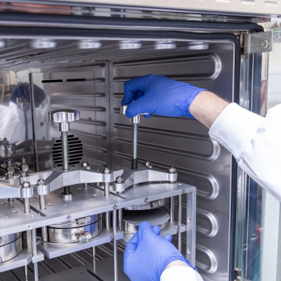 Gloved hands securing three metal cylinders to test hydrogen permeability 